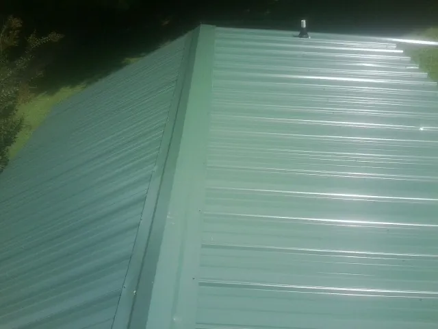 New green metal panels meeting at the ridge of a roof — Flat Roof Repair work by our crew in Alpine